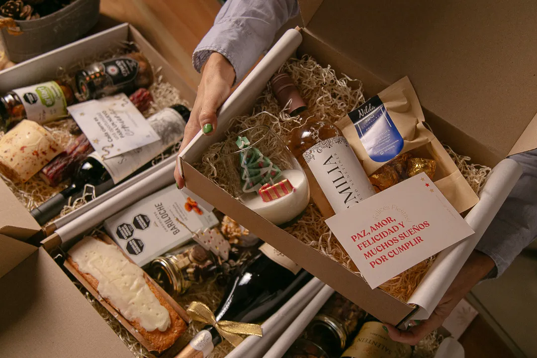Cajas navideñas de MondoBox abiertas, con tarjeta personalizada, espumante y delicatessen